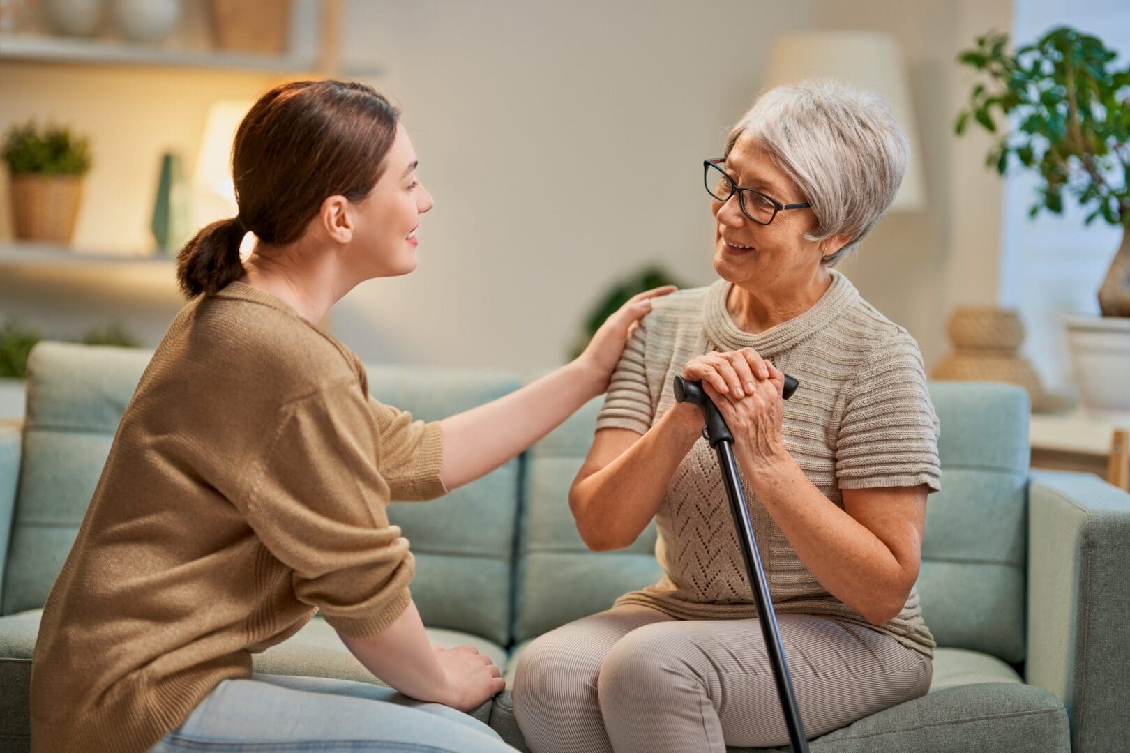 Young woman comforting elderly woman with cane